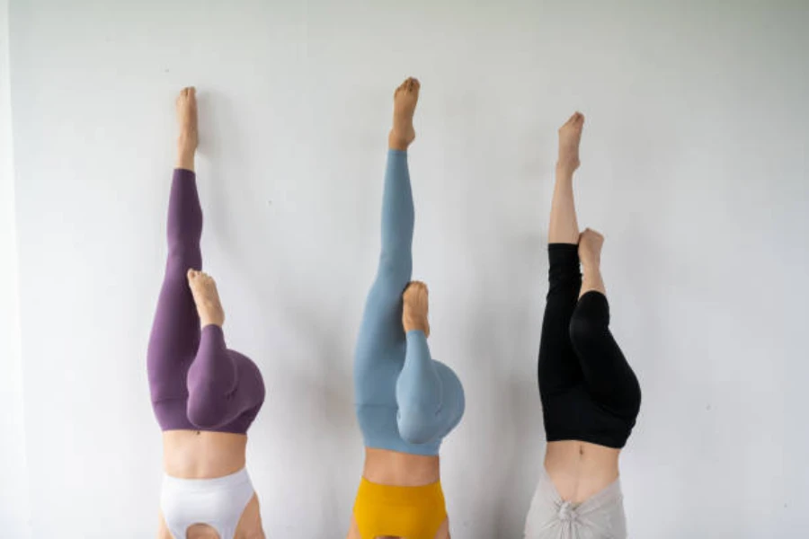 Three women wearing colorful leggings holding a headstand pose